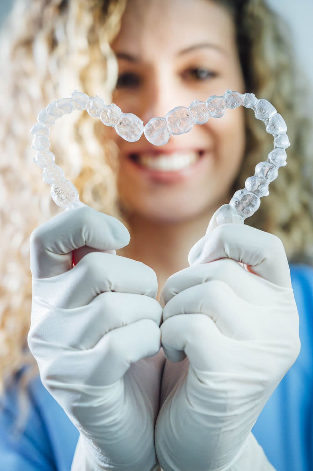 woman holding Invisalign aligners